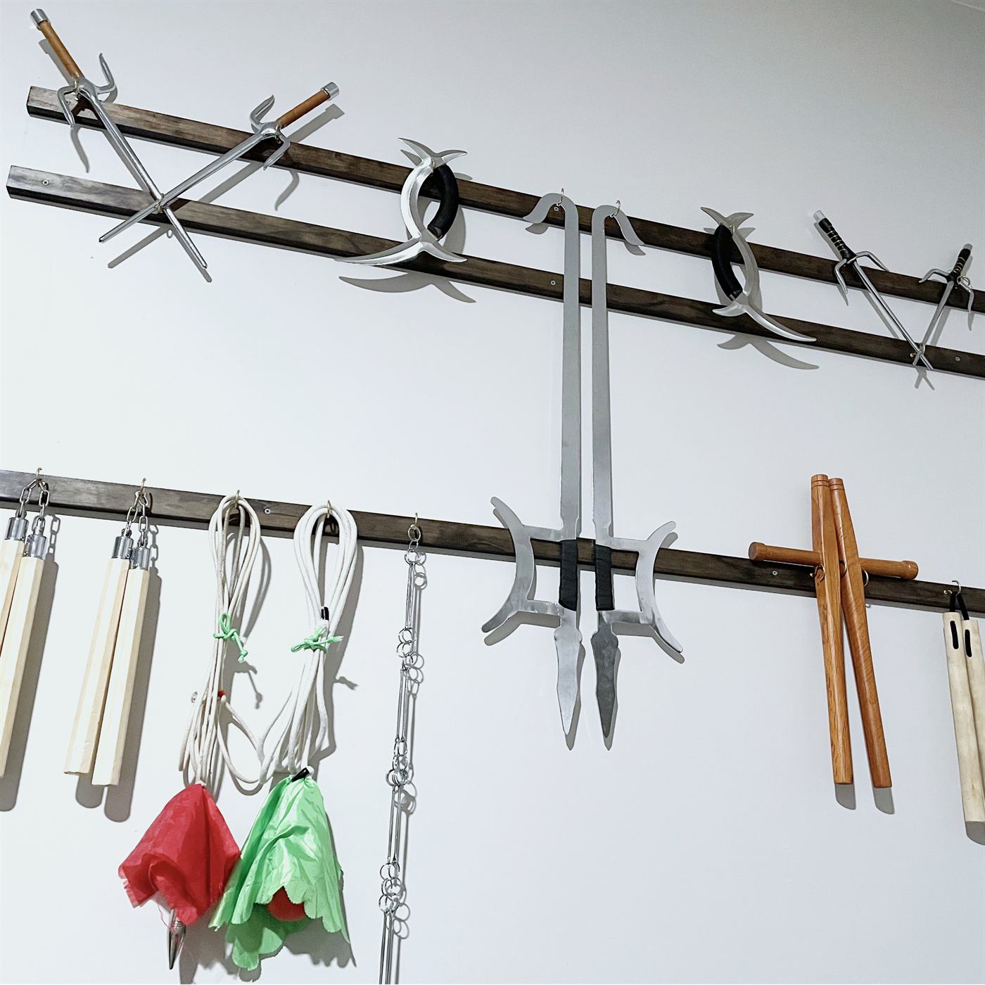 Training weapons on a studio wall, including swords, hooks, rope dart, staffs, and nunchaku.